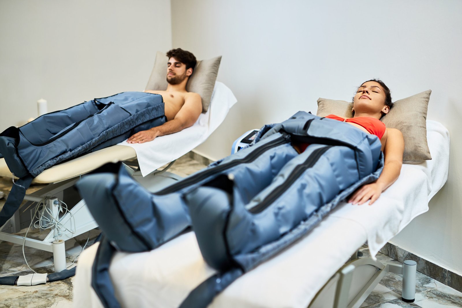 Young relaxed couple having a pressotherapy at health spa. Focus is on woman.